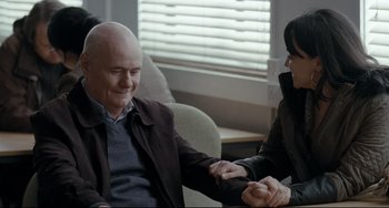 Movie still from “I, Daniel Blake” (2016), directed by Ken Loach – A man and a woman sitting in a chair holding hands; Medium shot, Over the shoulder angle