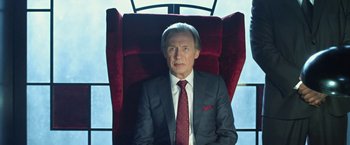 Movie still from “I, Frankenstein” (2014), directed by Stuart Beattie – A man in a suit and tie sitting in a chair; Medium shot, Low angle