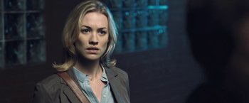 Movie still from “I, Frankenstein” (2014), directed by Stuart Beattie – A woman in a brown jacket is standing in a dark room; Close Up shot, Over the shoulder angle
