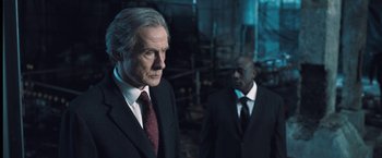 Movie still from “I, Frankenstein” (2014), directed by Stuart Beattie – A man in a suit and tie standing next to another man in a suit and tie; Medium shot, Over the shoulder angle