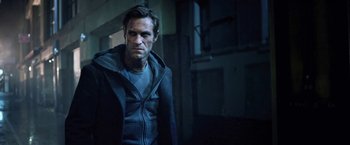 Movie still from “I, Frankenstein” (2014), directed by Stuart Beattie – A man wearing a hooded jacket standing in a dark room; Medium shot, Low angle