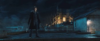 Movie still from “I, Frankenstein” (2014), directed by Stuart Beattie – A man holding a sword standing in front of a building; Wide shot, Low angle