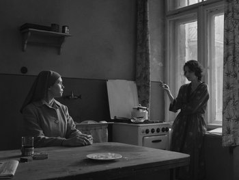 Movie still from “Ida” (2013), directed by Pawel Pawlikowski – Two women sit at a table in front of an open window; Medium shot, Low angle