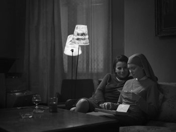Movie still from “Ida” (2013), directed by Pawel Pawlikowski – Two women sitting on a couch looking at a book; Medium shot, Low angle