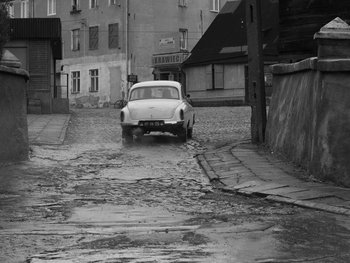 Movie still from “Ida” (2013), directed by Pawel Pawlikowski – An old car parked on a wet street in the rain; Wide shot, High angle