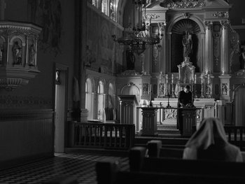 Movie still from “Ida” (2013), directed by Pawel Pawlikowski – A black - and - white photo of a church with a statue in the center of the room; Wide shot, Low angle