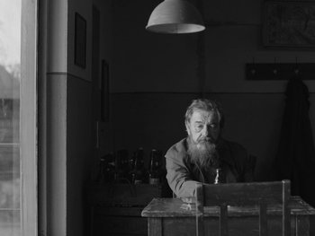 Movie still from “Ida” (2013), directed by Pawel Pawlikowski – An older man sitting at a table with a beard; Medium shot, Low angle