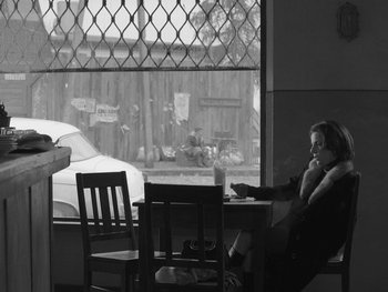 Movie still from “Ida” (2013), directed by Pawel Pawlikowski – A woman sitting at a table in front of a window; Wide shot, High angle