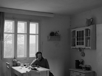 Movie still from “Ida” (2013), directed by Pawel Pawlikowski – A woman sitting at a table in front of a window; Wide shot, High angle