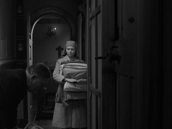 Movie still from “Ida” (2013), directed by Pawel Pawlikowski – A woman is carrying a stack of folded towels; Wide shot, Low angle