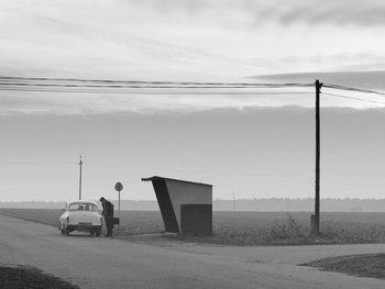 Movie still from “Ida” (2013), directed by Pawel Pawlikowski – A man standing on the side of a road next to a car; Extreme Wide shot, Low angle
