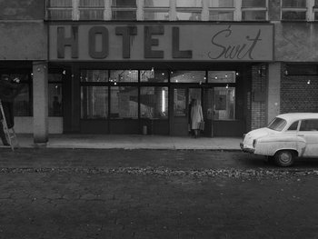 Movie still from “Ida” (2013), directed by Pawel Pawlikowski – A black - and - white photo of a hotel with a car parked in front of it; Wide shot, High angle