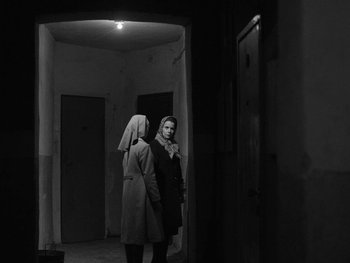 Movie still from “Ida” (2013), directed by Pawel Pawlikowski – Two women are standing in an empty hallway; Medium shot, Over the shoulder angle
