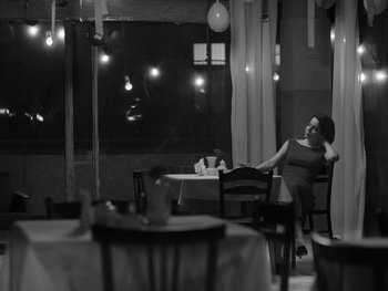 Movie still from “Ida” (2013), directed by Pawel Pawlikowski – A woman sitting at a table in front of a window; Wide shot, Low angle