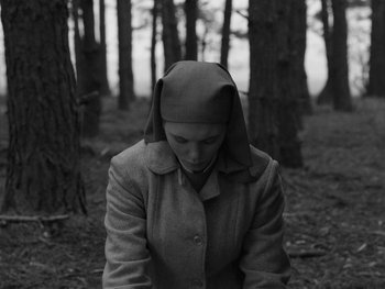 Movie still from “Ida” (2013), directed by Pawel Pawlikowski – A woman wearing a coat and a hat in the woods; Medium shot, High angle