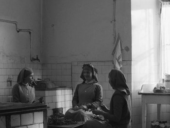 Movie still from “Ida” (2013), directed by Pawel Pawlikowski – Two women are sitting in a kitchen and one of the women is holding a knife; Wide shot, Low angle
