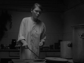 Movie still from “Ida” (2013), directed by Pawel Pawlikowski – A woman standing in front of a frying pan in a kitchen; Medium shot, Low angle