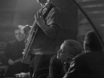Movie still from “Ida” (2013), directed by Pawel Pawlikowski – A woman sitting in front of a man holding a guitar; Medium shot, Over the shoulder angle