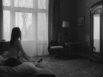Movie still from “Ida” (2013), directed by Pawel Pawlikowski – A woman sitting on a bed looking out a window; Wide shot, Over the shoulder angle