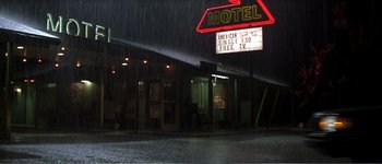 Movie still from “Identity” (2003), directed by James Mangold – A motel sign lit up in the rain at night; Extreme Wide shot, High angle