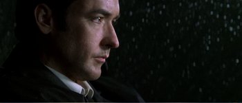Movie still from “Identity” (2003), directed by James Mangold – A person wearing a suit and tie; Close Up shot, Low angle