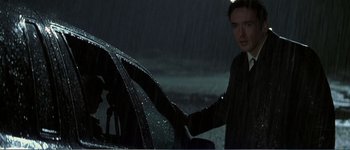 Movie still from “Identity” (2003), directed by James Mangold – A man standing next to a parked car in the rain; Medium shot, Low angle
