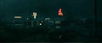 Movie still from “Identity” (2003), directed by James Mangold – A motel sign lit up at night in the rain; Extreme Wide shot, High angle