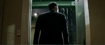 Movie still from “Identity” (2003), directed by James Mangold – A man in a suit standing in front of a rain shower; Medium shot, Low angle