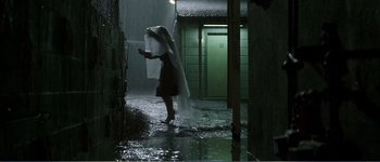 Movie still from “Identity” (2003), directed by James Mangold – A woman with a white umbrella walking in the rain; Wide shot, Low angle