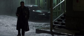 Movie still from “Identity” (2003), directed by James Mangold – A man standing in the rain next to a car; Wide shot, Low angle