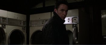 Movie still from “Identity” (2003), directed by James Mangold – A man standing in front of a washing machine; Medium shot, Low angle