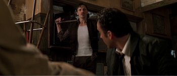 Movie still from “Identity” (2003), directed by James Mangold – A man holding a baseball bat in front of another man; Medium shot, Over the shoulder angle