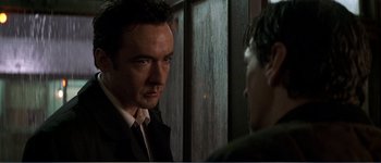 Movie still from “Identity” (2003), directed by James Mangold – A man wearing a suit and tie standing next to another man in a suit; Close Up shot, Over the shoulder angle
