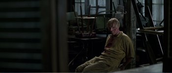 Movie still from “Identity” (2003), directed by James Mangold – A man sitting on the ground in a room; Wide shot, High angle