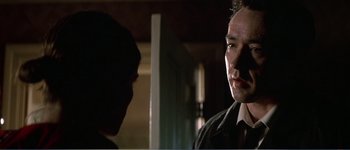 Movie still from “Identity” (2003), directed by James Mangold – A man standing next to another man in a dark room; Close Up shot, Over the shoulder angle
