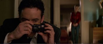 Movie still from “Identity” (2003), directed by James Mangold – A man taking a picture with a camera; Close Up shot, Low angle