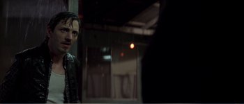 Movie still from “Identity” (2003), directed by James Mangold – A man standing next to a wall in a dark room; Close Up shot, Over the shoulder angle