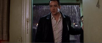 Movie still from “Identity” (2003), directed by James Mangold – A man standing in front of a window in the rain; Medium shot, Low angle