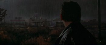 Movie still from “Identity” (2003), directed by James Mangold – A man standing in the rain looking at a hotel; Extreme Wide shot, Over the shoulder angle