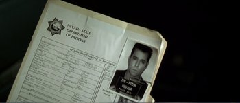 Movie still from “Identity” (2003), directed by James Mangold – An inmate's mugshot is shown on a prison inmate's record book; Extreme Close Up shot, Overhead angle