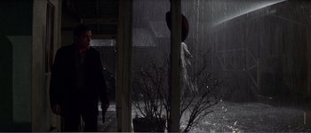 Movie still from “Identity” (2003), directed by James Mangold – A man standing in front of a window in the rain; Wide shot, Low angle