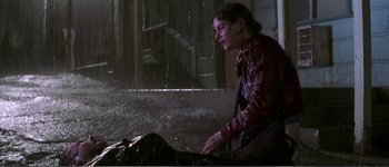 Movie still from “Identity” (2003), directed by James Mangold – A woman sitting on the ground in the rain; Wide shot, Overhead angle