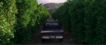 Movie still from “Identity” (2003), directed by James Mangold – A truck driving down a dirt road near a forest; Extreme Wide shot, High angle