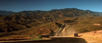 Movie still from “Identity” (2003), directed by James Mangold – A dirt road going through the middle of the desert; Extreme Wide shot, High angle