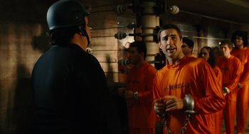 Movie still from “Idiocracy” (2006), directed by Mike Judge – A group of men in orange shirts standing next to each other; Medium shot, Over the shoulder angle