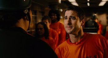 Movie still from “Idiocracy” (2006), directed by Mike Judge – A group of people in orange shirts standing next to each other; Close Up shot, Over the shoulder angle