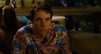 Movie still from “Idiocracy” (2006), directed by Mike Judge – A man in a colorful shirt sitting in front of a wall; Close Up shot, Over the shoulder angle