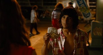 Movie still from “Idiocracy” (2006), directed by Mike Judge – A man holding a bunch of money while standing on a sidewalk; Medium shot, Over the shoulder angle