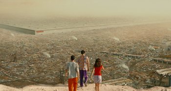 Movie still from “Idiocracy” (2006), directed by Mike Judge – Three people are standing on a hill overlooking a city; Extreme Wide shot, High angle