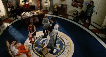 Movie still from “Idiocracy” (2006), directed by Mike Judge – A group of people standing on top of a floor in a room; Wide shot, High angle